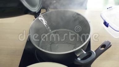 在厨房里用水壶把开水倒入锅中